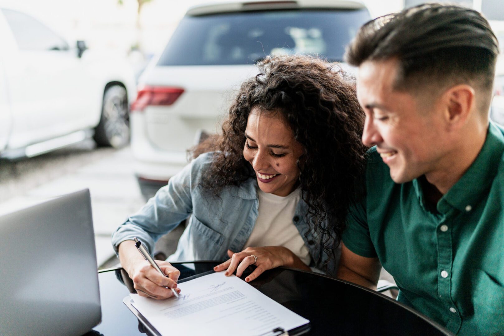 Couple signing document at outdoor table.