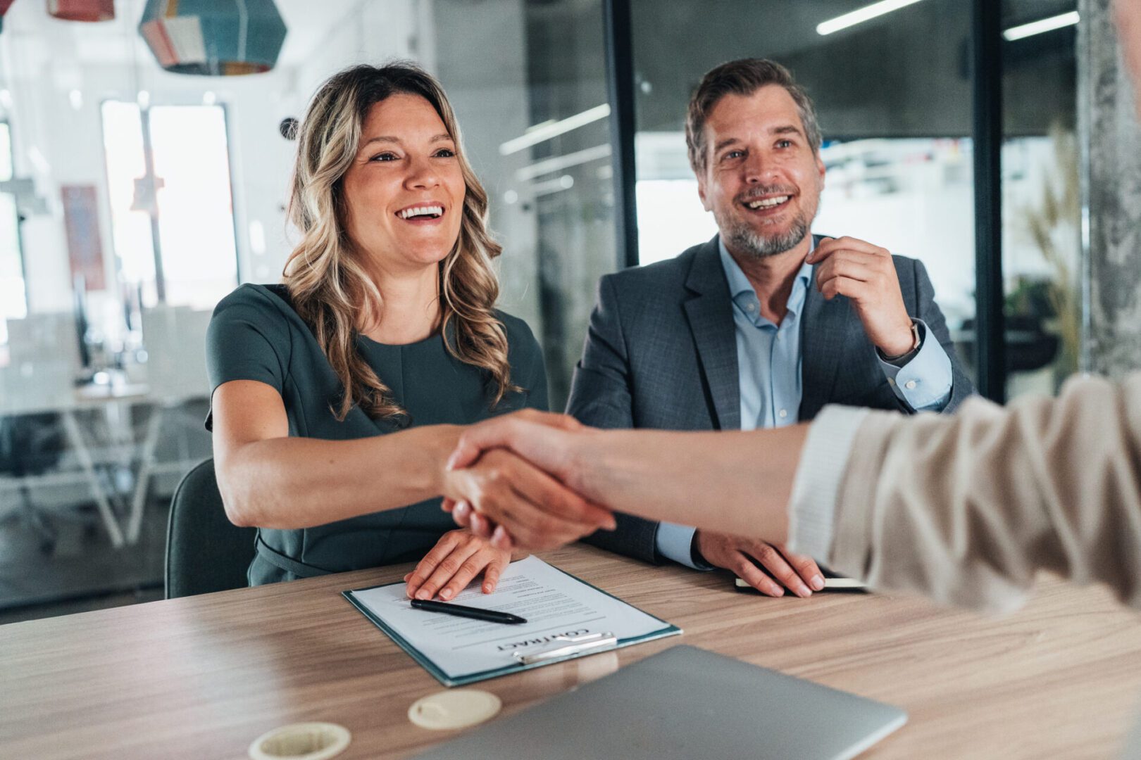 Handshake during a business meeting, smiling professionals.